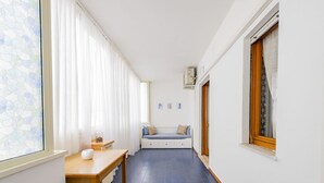 Un couloir étroit avec un banc, une table et une fenêtre ornée de rideaux.