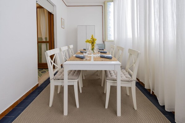A dining area with a white table, four chairs, and a vase of yellow flowers.