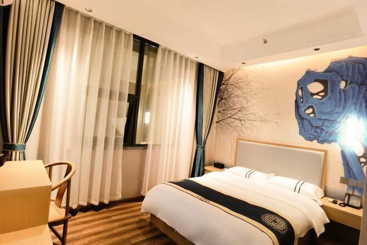 Habitación de hotel con cama, una silla, un escritorio, una lámpara y un diseño único en la pared.