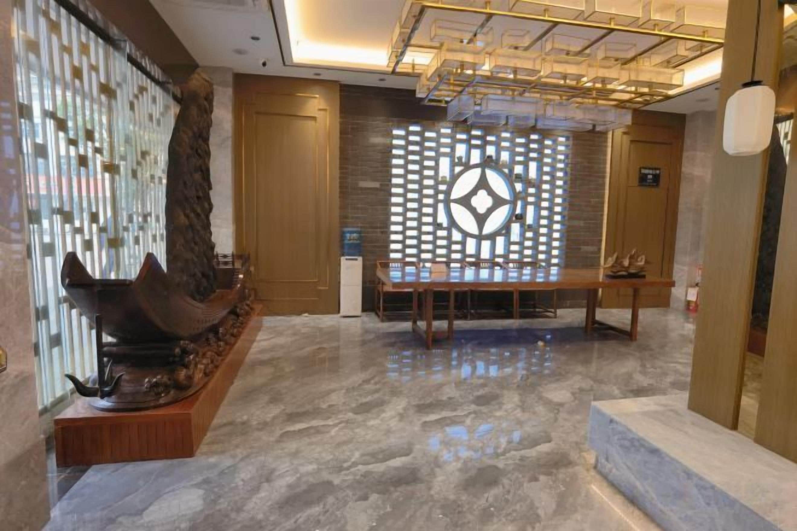 A lobby with a reception desk, a decorative wall, and a seating area.