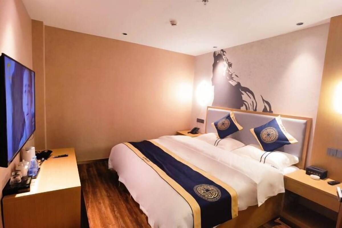 Habitación de hotel con una cama grande, televisión, escritorio y una obra de arte colgada en la pared.