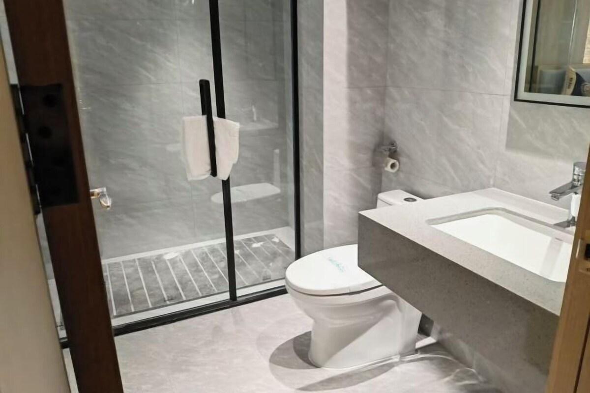 A modern bathroom with a glass shower enclosure, a toilet, and a sink.