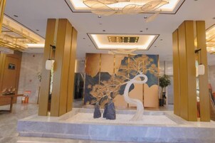 Un vestíbulo con una instalación artística central, un mostrador de recepción y una escalera.