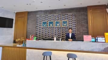A reception desk with a modern design, a counter, and a seating area with stools.