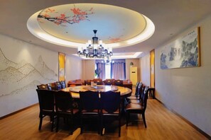 A dining area with a round table, chairs, a chandelier, and artwork on the walls. - Luocheng Fengxucheng Hotel (Luocheng)