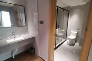 A modern bathroom with a large mirror, a white sink, a glass shower enclosure, and a toilet. - Luocheng Fengxucheng Hotel (Luocheng)