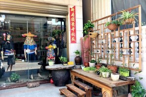 A storefront with mannequins displaying clothing, a wooden table with potted plants, and a decorative wooden lattice. - Tingtaoge Inn, 186 Qianchao, Hui'an (Hui'an)
