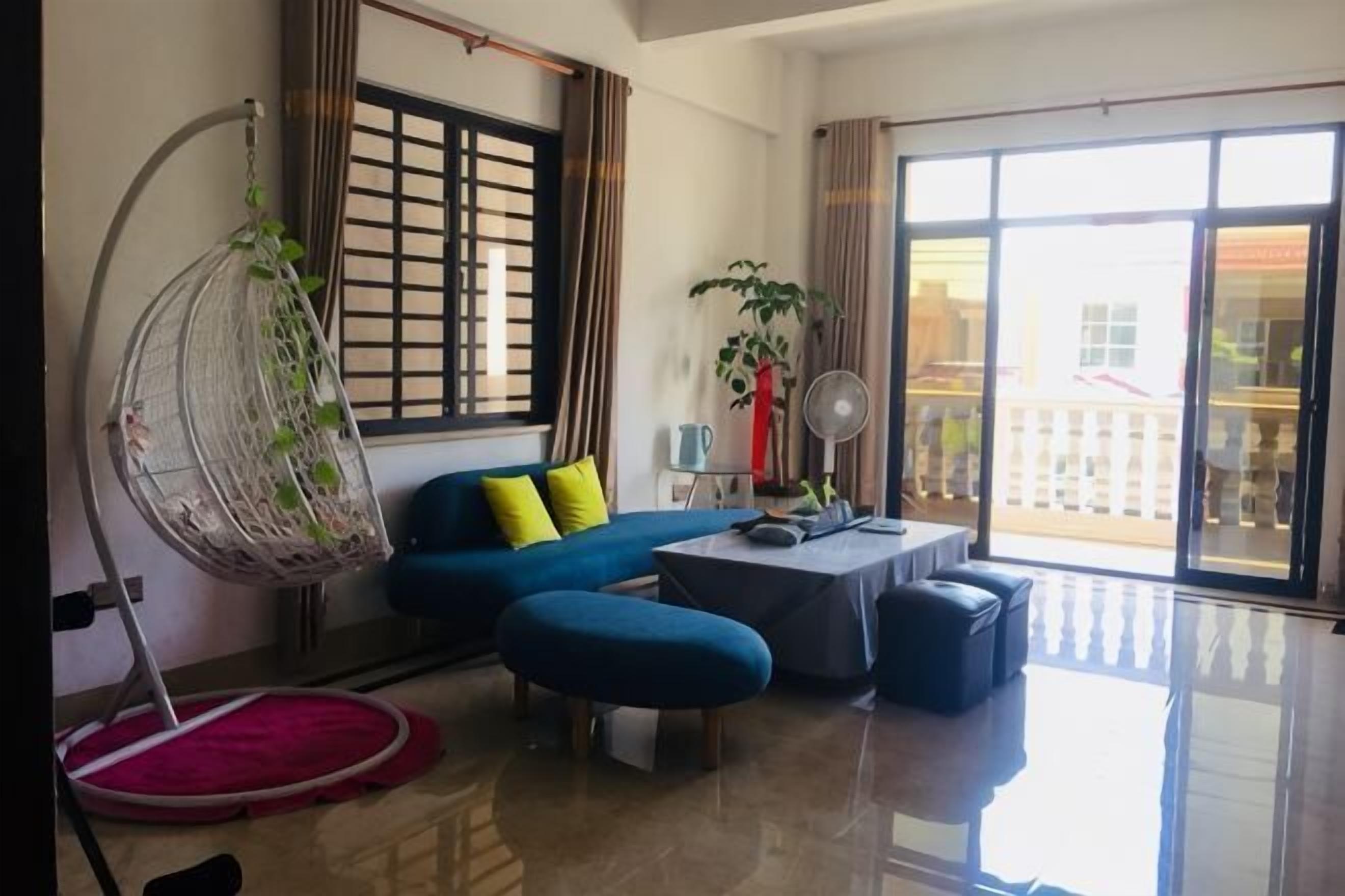 Un salon avec un fauteuil suspendu, un canapé, une table et un balcon offrant une vue dégagée.