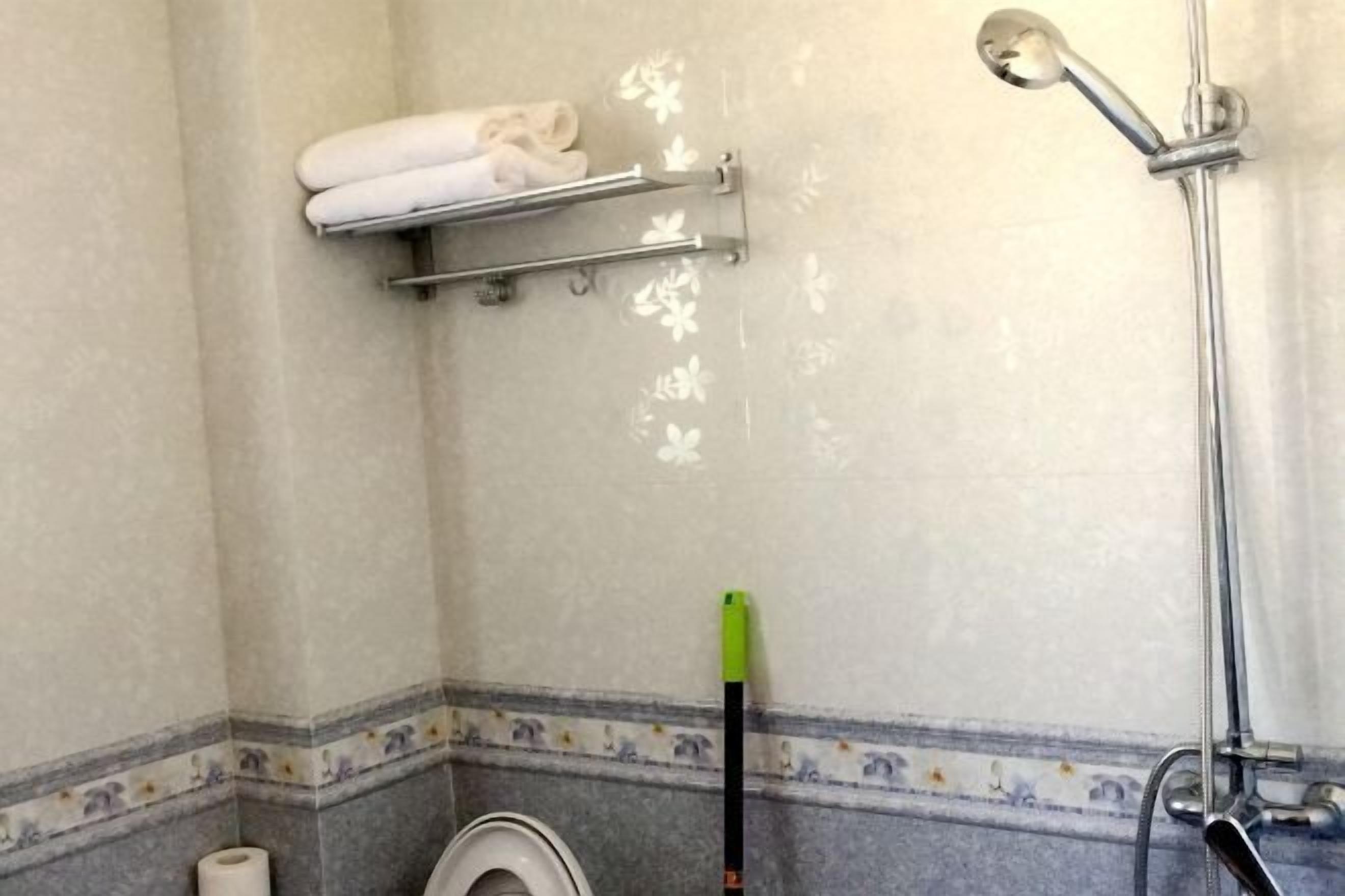 A bathroom with a shower, a toilet, and a towel rack.