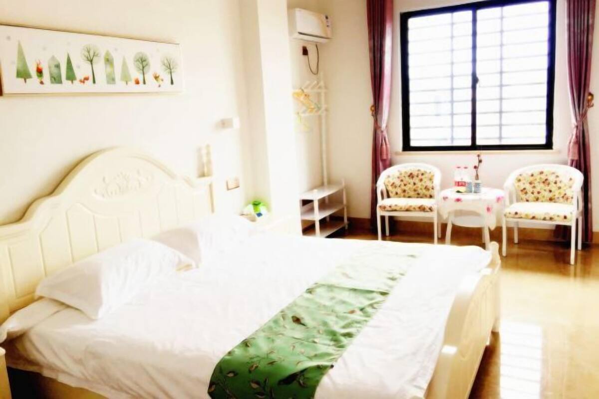 A hotel room with a bed, two chairs, a small table, and a window with curtains.