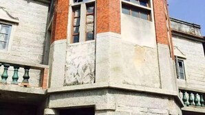 Un coin d’un bâtiment aux murs en pierre et à la partie en briques rouges.