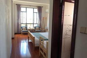 Une pièce comprenant un lit, deux chaises, un bureau et une fenêtre avec des rideaux.