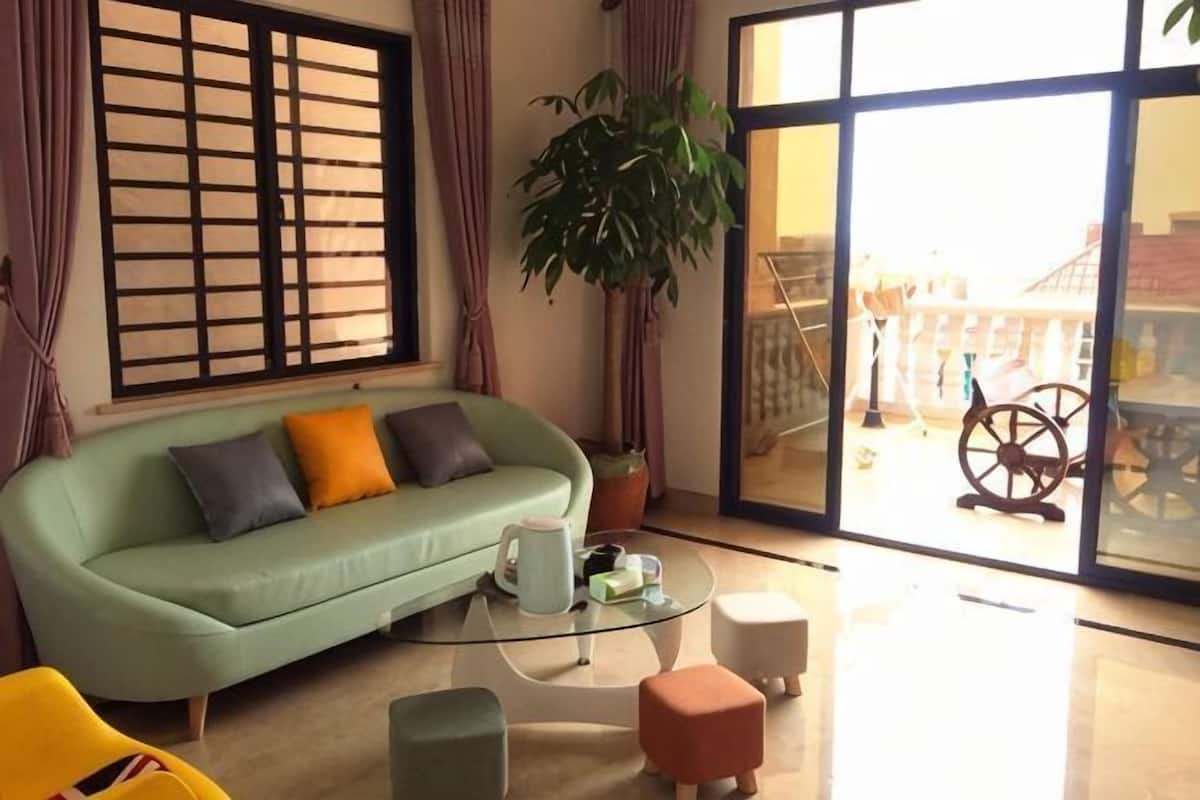 A living room with a sofa, a coffee table, and a large window with a view.