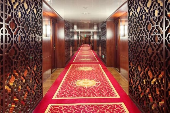 Un pasillo con alfombra roja, paneles de madera y un diseño estampado.