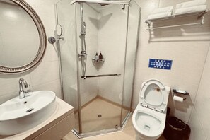 A bathroom with a glass-enclosed shower, a sink, and a toilet. - Guoli Holiday Hotel (Ying County)
