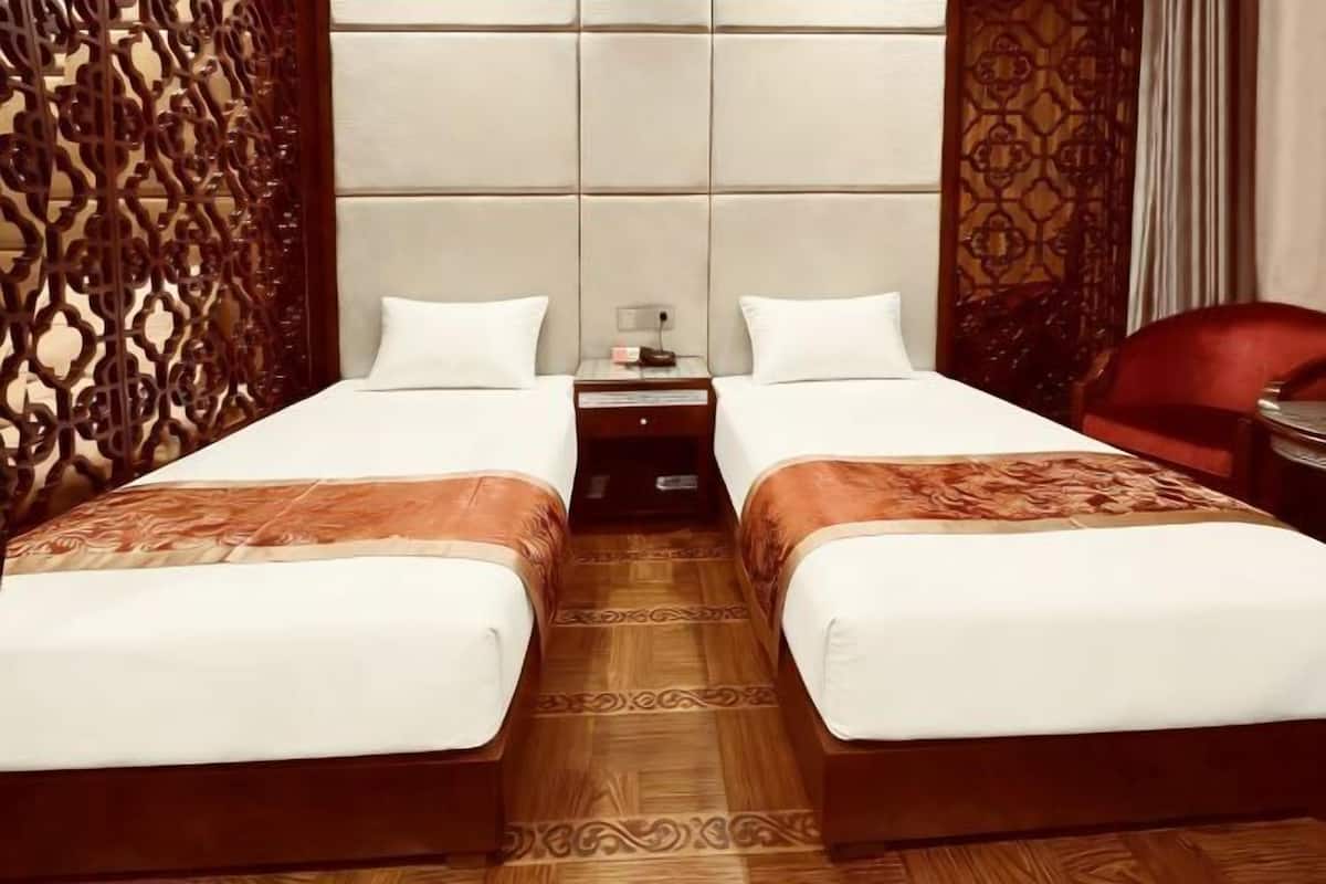 A double bed with a headboard, a nightstand, and a red chair.