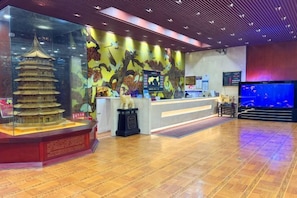 A reception area with a traditional pagoda model, a counter, and a large aquarium. - Guoli Holiday Hotel (Ying County)