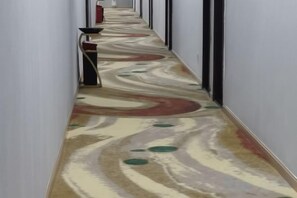 A hallway with a patterned carpet and a red chair. - Guangzhou Jintan Fashion Hotel (Zhongluotan Subway Station) (Guangzhou)