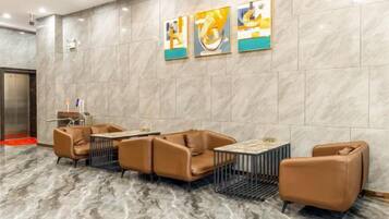 A lobby with marble flooring, a reception desk, and brown leather seating.