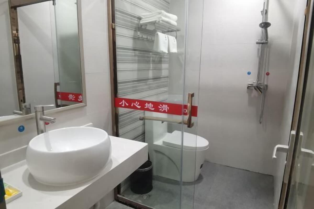 Une salle de bain avec un lavabo blanc, des toilettes et une douche à parois en verre.