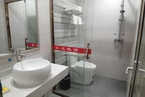 Une salle de bain avec un lavabo blanc, des toilettes et une douche à parois en verre.