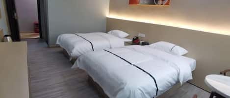 A hotel room with two beds, a small table, and a painting on the wall.