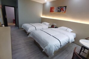 Une chambre d’hôtel avec deux lits, une petite table et un tableau au mur.