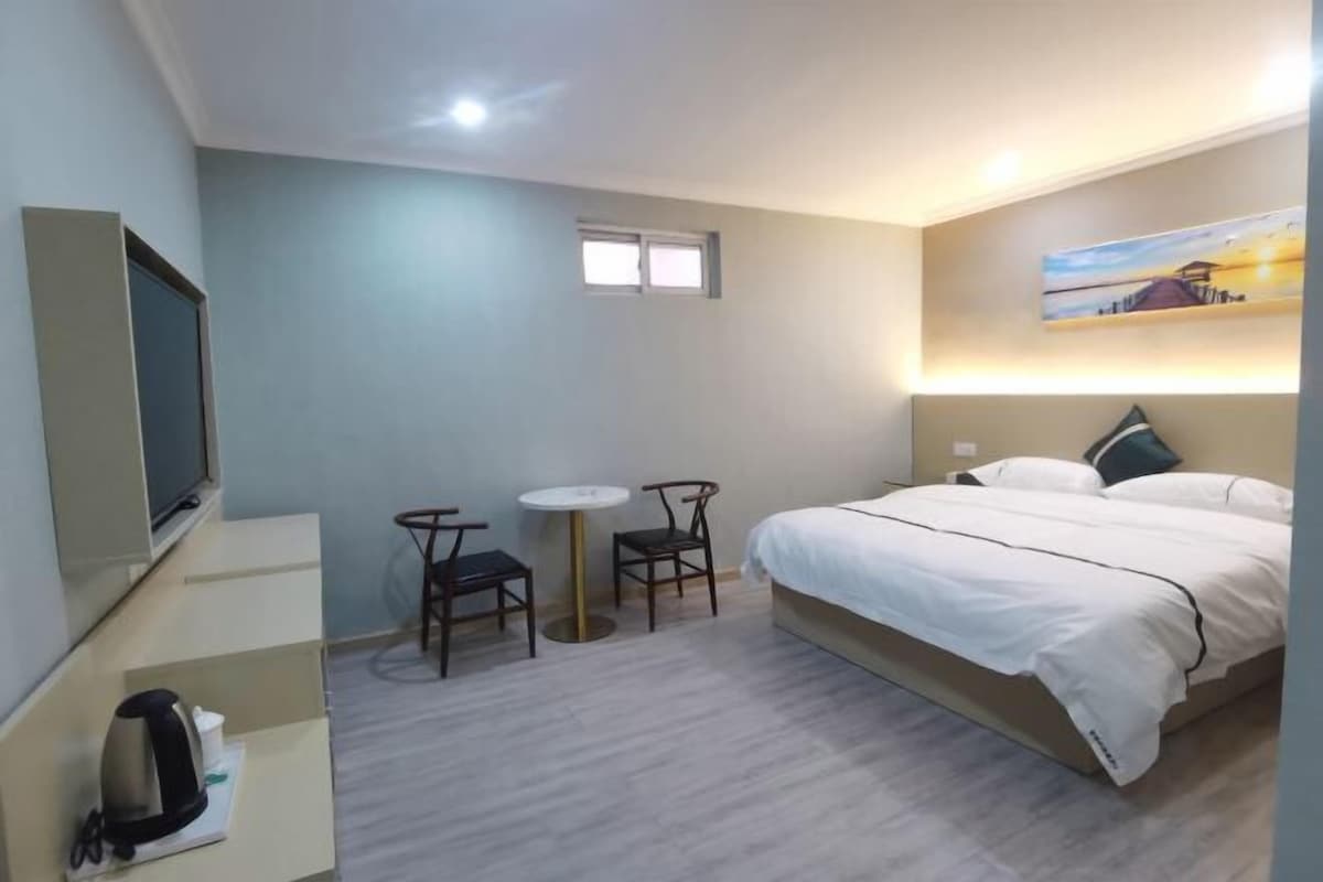 Une chambre d’hôtel avec un lit, une télévision, une petite table, deux chaises et une fenêtre.