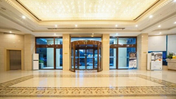 A hotel lobby with a large chandelier, a revolving door, and a reception desk.