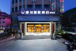 A hotel entrance with a sign, steps leading up to the door, and a parking area with vehicles. - man'zhouguo'ji'jiu'dian（anhuaxiyuejiudian) (Anhua)