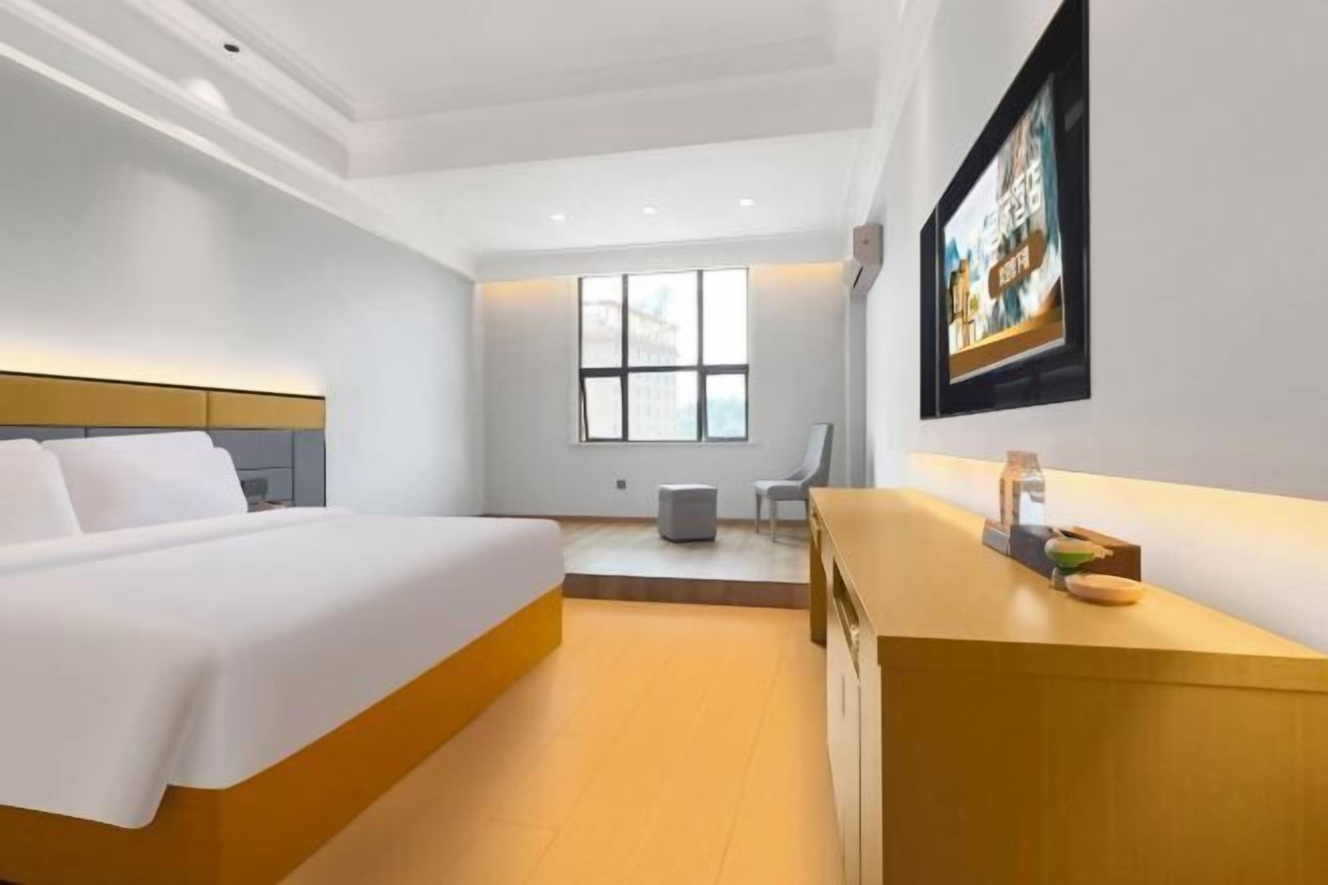 Une chambre d’hôtel moderne, dotée d’un grand lit, d’un bureau, d’une chaise, d’une fenêtre et d’un téléviseur fixé au mur.