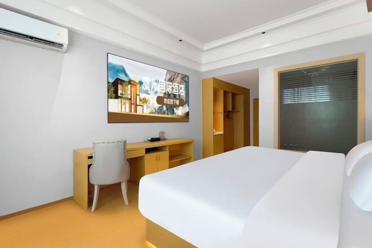 Una habitación de hotel con cama, escritorio, silla, televisor y armario.