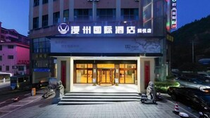 A hotel entrance with a glass door, a signboard, and a few parked scooters.
