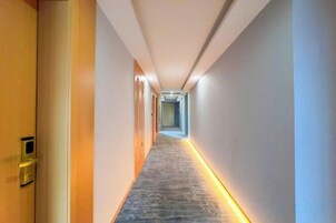 Un pasillo con piso alfombrado y una tira de luz a lo largo de la pared.
