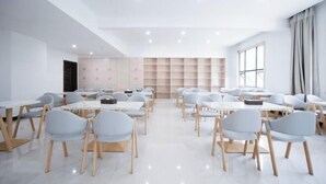 A modern classroom with white walls, grey chairs, and tables arranged in rows.