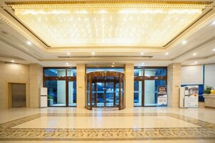 Un hall de hotel con puerta giratoria, mostrador de recepción y alfombra estampada.