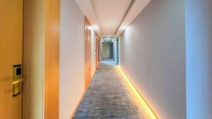 A long, narrow hallway with a patterned carpet and a yellow underfloor lighting strip.