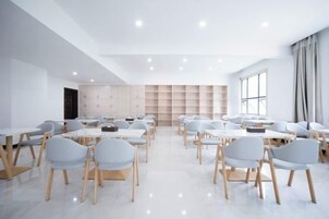 Una habitación amplia con varias mesas y sillas, un ventanal grande y un armario de madera.