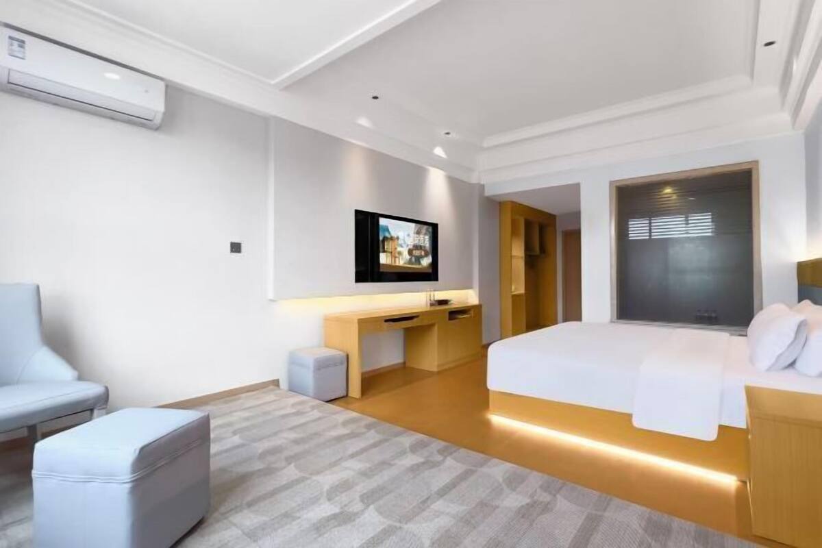 Quarto de hotel moderno com uma cama, uma escrivaninha, uma cadeira e uma televisão.
