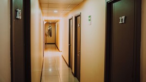 Pasillo de hotel con puertas numeradas 17 y 18, suelo de baldosas e iluminación empotrada en el techo.