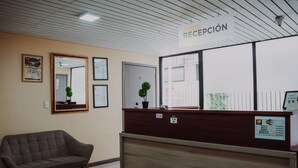 Zona de recepción con mostrador, sofá, cuadros enmarcados en la pared y señalización indicando disponibilidad de WiFi.