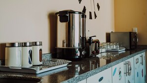 Una encimera de cocina con una cafetera, una balanza y un hervidor.