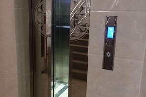 Un ascenseur doté d’un écran numérique et d’une porte en verre.