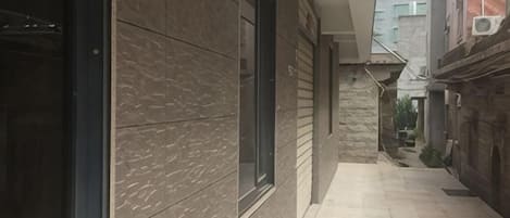 A narrow corridor with a tiled floor leading to a building entrance.