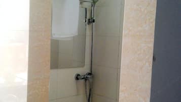 A shower with a handheld showerhead and a wall-mounted faucet.