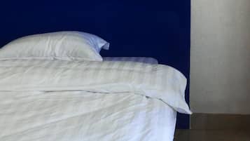 A bed with white bedding in a room with a blue wall and a white door.
