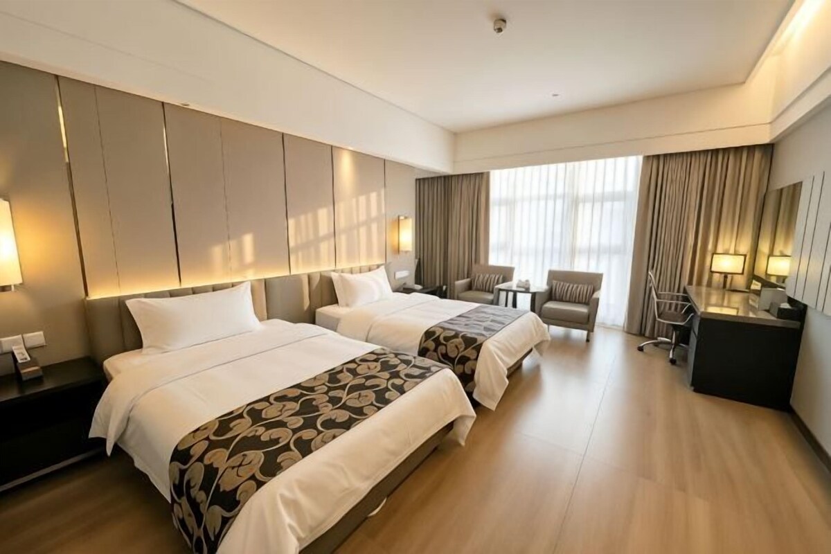 Ein Hotelzimmer mit zwei Betten, einem Schreibtisch, einem Stuhl und einem kleinen Tisch.