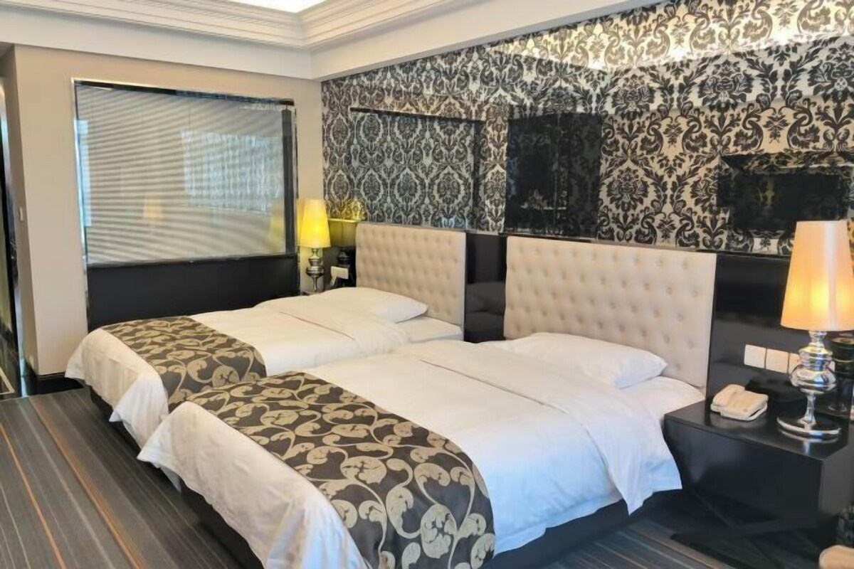 Een hotelkamer met een groot bed, een nachtkastje met een lamp en een aan de muur bevestigde televisie.