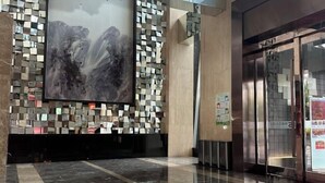 A lobby with a large abstract painting, a mosaic wall, and a modern elevator. - Huasheng Shaxian Boutique Hotel (Sanming)
