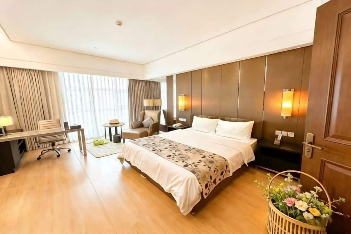Habitación de hotel con cama, escritorio, silla y una mesita.